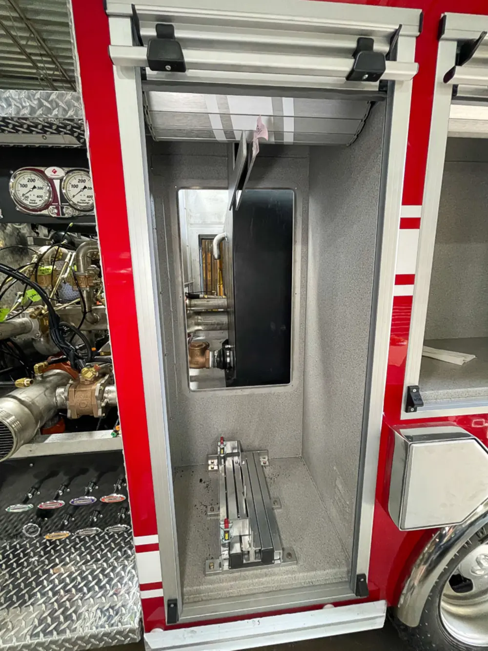 Exterior view of small fire truck showing cab, body compartments, and wheel/tire area.